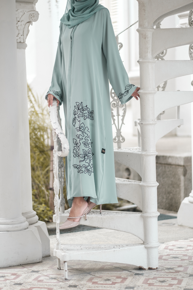 Close up of Muslimah Model wearing modest nidha abaya in blue with floral, pleated details on sleeves and hem