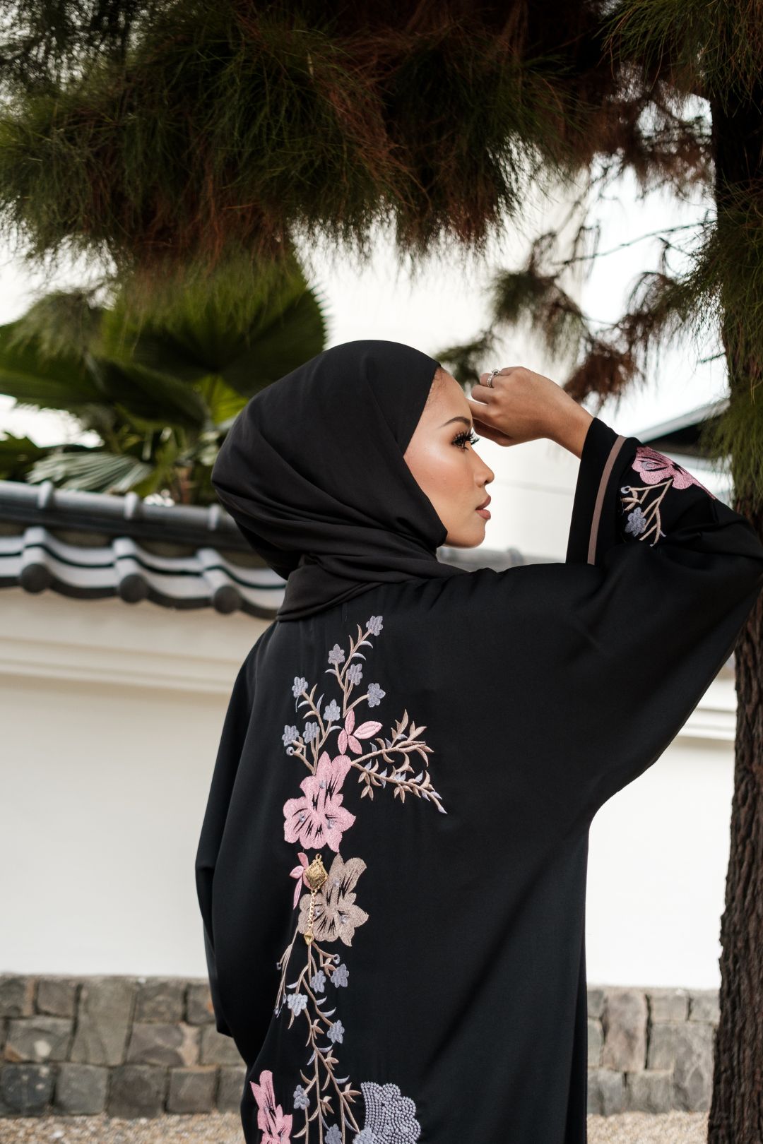 Singapore Muslimah model in hijab wearing black nidha closed abaya with pink and blue floral embroidery. 