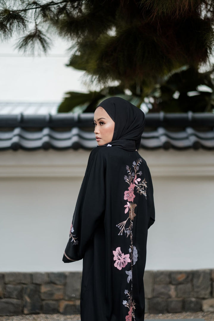 Singapore Muslimah model in hijab wearing black nidha closed abaya with pink and blue floral embroidery. 