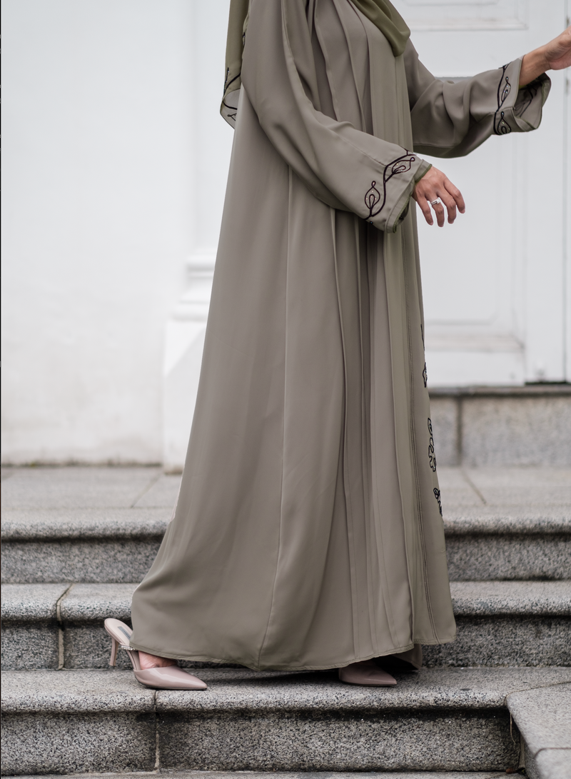 Close up of Muslimah Model wearing modest nidha abaya in olive with floral, pleated details on sleeves and hem